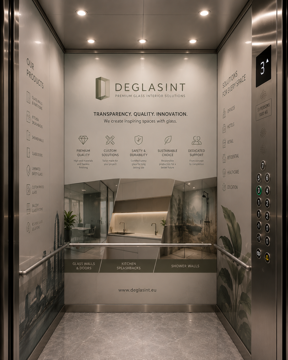 An interior view of an elevator cabin with a large wall display for Deglasint premium glass interior solutions. The metallic elevator walls and floor surround a printed panel showing glass wall and kitchen splashwall designs, with the Deglasint logo and product information prominently visible.