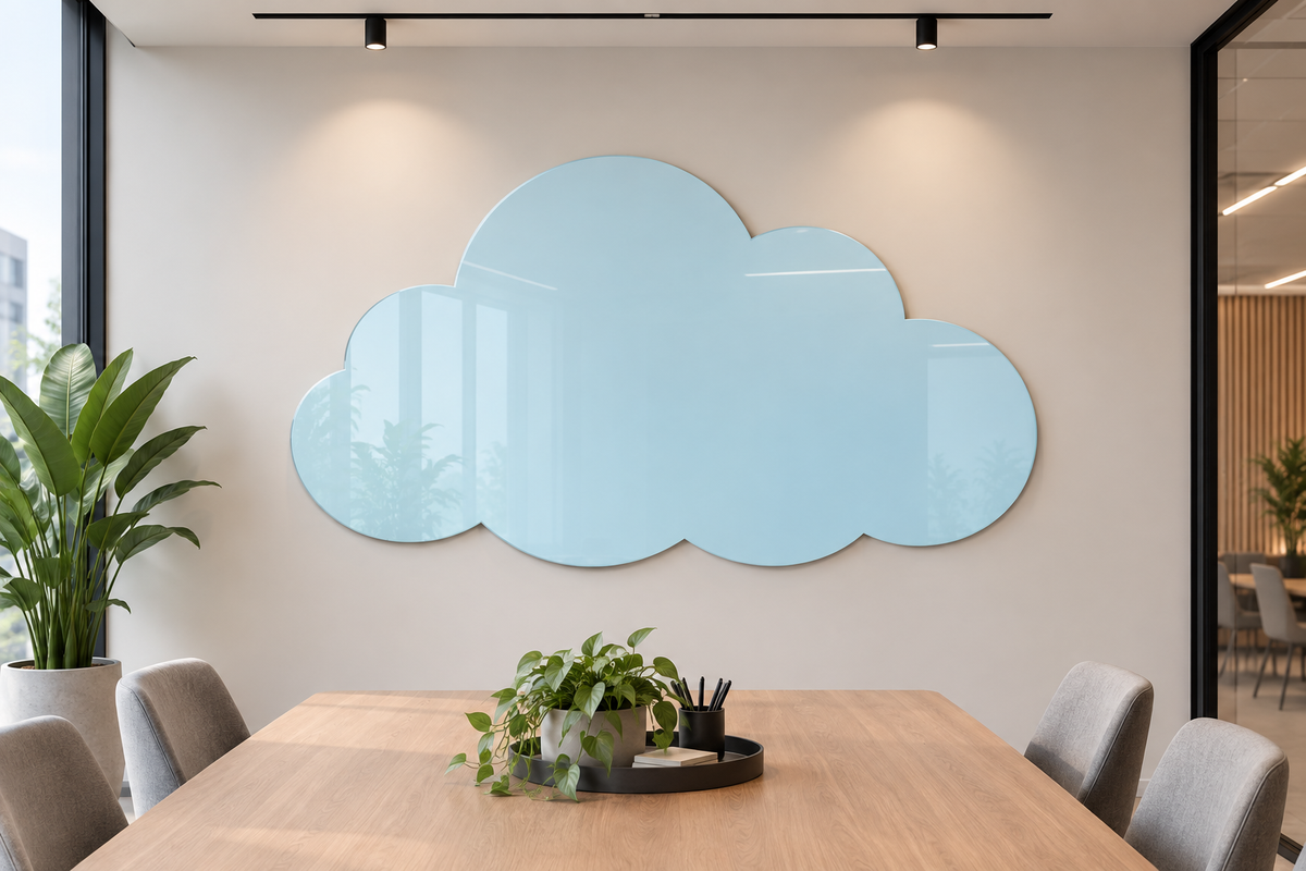 A large, cloud-shaped light blue wall mirror hangs on a beige wall in a modern office setting, above a wooden conference table with gray chairs and potted plants.